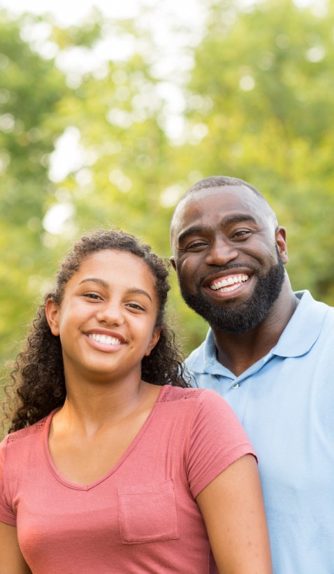 black father and daughter smiling together outdoors in summer